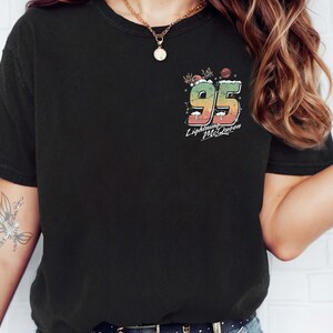 Puede incluir: Camiseta negra con un gr&aacute;fico colorido del n&uacute;mero 95 y el texto "Lightning McQueen".