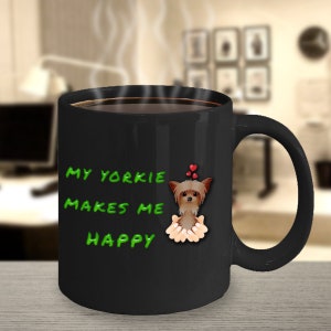 Puede incluir: Taza de café negra con una ilustración de un perro Yorkshire Terrier blanco y el texto "My Yorkie Makes Me Happy" en verde.