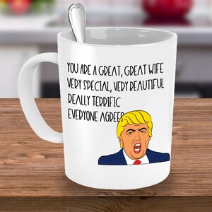 Puede incluir: Taza de café de cerámica blanca con una ilustración en blanco y negro de un hombre con cabello rubio y corbata roja. El texto en la taza dice "You are a great, great wife very special, very beautiful really terrific everyone agrees."