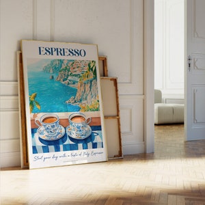 May include: A poster with a watercolor illustration of a coastal Italian landscape with two cups of espresso on a striped table cloth. The poster has the text "ESPRESSO" in large blue letters and the text "Start your day with a taste of Italy Espresso" in smaller blue letters.