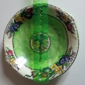 May include: A green and white ceramic bowl with a floral design. The bowl is approximately 10 inches in diameter.