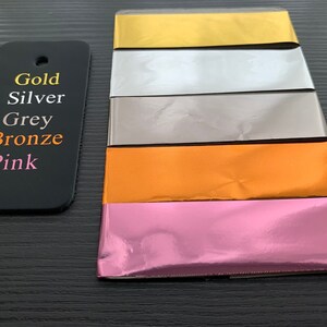 Puede incluir: Cinco l&aacute;minas met&aacute;licas de papel en diferentes colores: dorado, plateado, gris, bronce y rosa. Las l&aacute;minas est&aacute;n apiladas una encima de la otra, con la l&aacute;mina dorada en la parte superior y la l&aacute;mina rosa en la parte inferior.