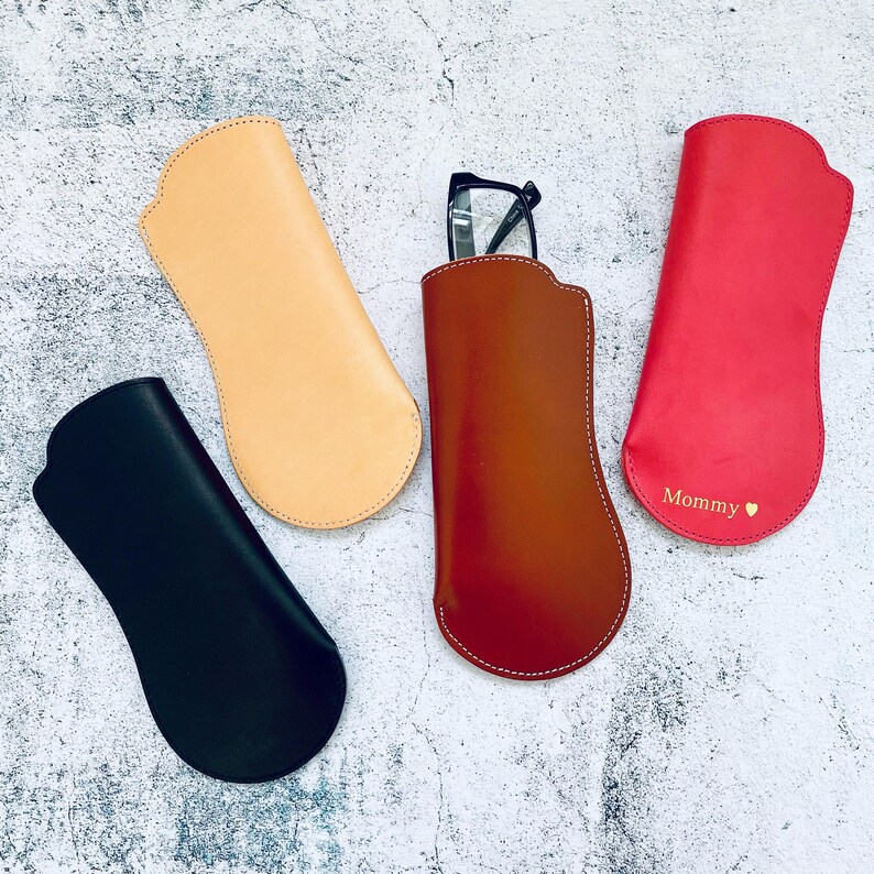 Puede incluir: Cuatro estuches para gafas de cuero de diferentes colores. Un estuche es rojo con la palabra "Mommy" y un coraz&oacute;n. Un estuche es marr&oacute;n, uno es negro y uno es beige.