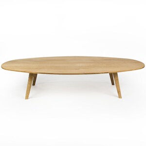 May include: A light wood oval coffee table with four tapered legs.