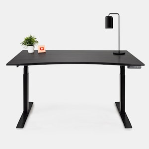 Peut inclure: Bureau debout noir avec un plateau incurvé et une lampe noire sur le côté droit. Une petite plante en pot et une carte de note se trouvent sur le côté gauche du bureau.