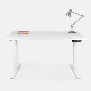 Peut inclure: Un bureau debout blanc avec une lampe de bureau argentée et un livre sur la surface.