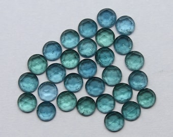 May include: A collection of 25 round, faceted, blue-green gemstones. The gemstones are arranged in a loose, triangular shape.