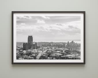 May include: A black and white aerial photograph of a city with a large cathedral in the center. The city is surrounded by water and there are clouds in the sky.