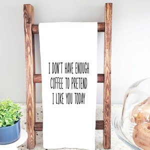 May include: White kitchen towel with the text "I don't have enough coffee to pretend I like you today" printed in black.