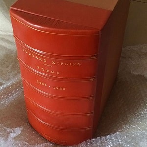 May include: A red leather-bound book with gold lettering. The title is "Rudyard Kipling Poems 1886 - 1929".