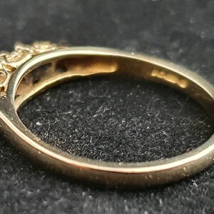 K&ouml;nnte beinhalten: Ein Goldring mit einer Reihe kleiner, klarer Steine, die in die Band gefasst sind.