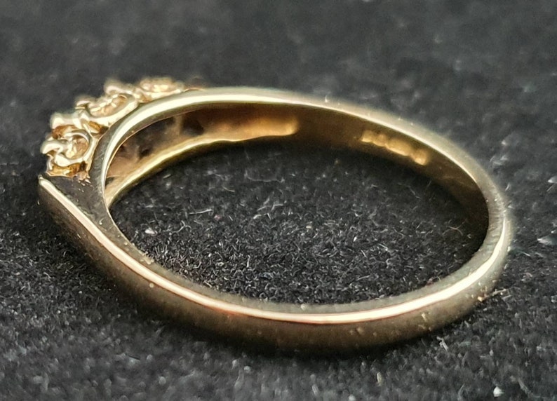 K&ouml;nnte beinhalten: Ein Goldring mit einer Reihe kleiner, klarer Steine, die in die Band gefasst sind.