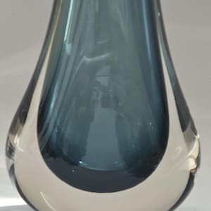 May include: A clear glass vase with a dark blue interior. The vase has a rounded, teardrop shape with a wide opening at the top.