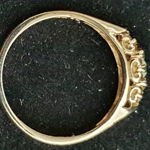 K&ouml;nnte beinhalten: Ein goldener Ring mit drei ovalen Edelsteinen, die in einem dekorativen Band gefasst sind.