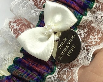 May include: White lace garter with a blue, green, and red plaid ribbon. A white satin bow with pearl accents is attached to a silver charm that says "YOUR ENGRAVING HERE".