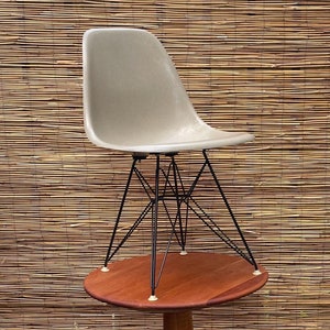 May include: A beige fiberglass chair with black metal legs sits on top of a round wooden table with a pedestal base.