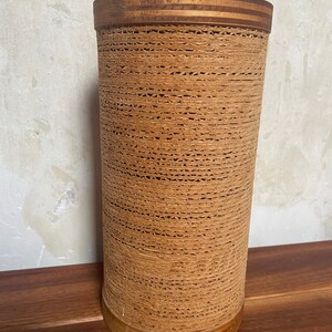 May include: A brown woven lamp base with a wooden top and bottom. The base is made of a woven material that looks like rope.