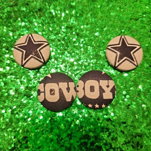 May include: Three fabric buttons with a green glitter background. Two buttons have a white star on a black background. One button has the word "COWBOY" in white letters on a black background.