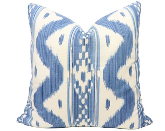 May include: A blue and white patterned throw pillow with an ikat design. The pillow is made of a soft, woven fabric.