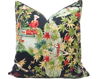 May include: Black pillow with a colorful floral and bird print. The print features a scene with people, trees, and birds.