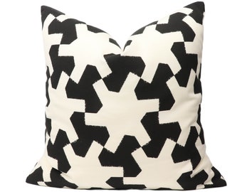 May include: A square throw pillow featuring a high-contrast black and off-white geometric pattern. The design consists of repeating, interlocking star-like shapes with jagged, brush-stroke edges that cover the entire front surface of the pillow.