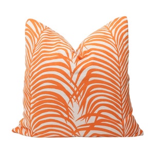 May include: Orange and white throw pillow with a palm leaf pattern.
