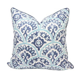 May include: A blue and white patterned throw pillow with a navy blue border. The pattern features a repeating design of stylized flowers and leaves.