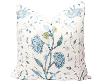 May include: A white pillow with a blue and green floral pattern. The pillow features a repeating design of stylized flowers and leaves.