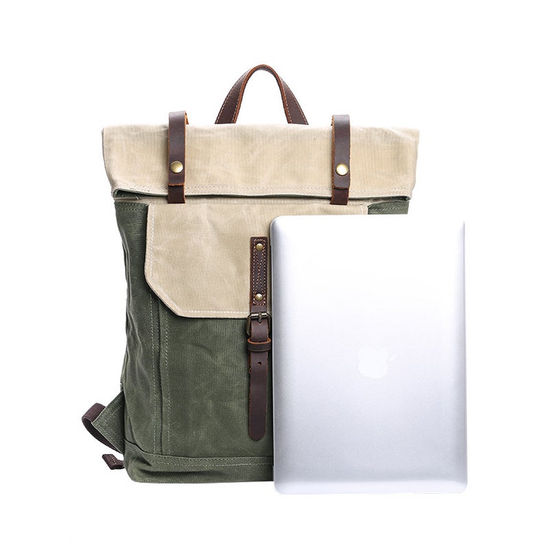 May include: A green and beige canvas backpack with brown leather straps and buckles. The backpack has a flap that folds over the top and a laptop compartment.
