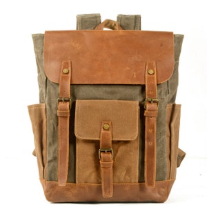 May include: A brown leather and green canvas backpack with multiple pockets and buckles.