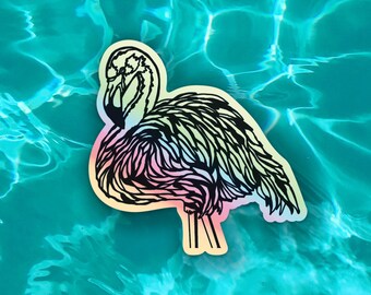 May include: A holographic sticker of a flamingo, featuring a black outline and a gradient of colors. The sticker is placed on a turquoise surface, creating a vibrant contrast. The flamingo design is detailed and eye-catching.