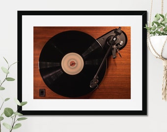May include: A black vinyl record on a turntable with a wooden base. The record is spinning and the needle is in the groove.