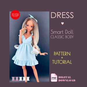 May include: A Smart Doll in a light blue gingham dress with a frilled hem. The doll has long blonde hair and a blue bow. The image includes text that says "DRESS", "Smart Doll CLASSIC BODY", "PATTERN + TUTORIAL", and "DIGITAL DOWNLOAD".