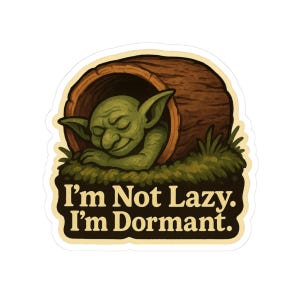 May include: A sticker featuring a green goblin sleeping inside a brown log. The goblin is resting on green grass. The text on the sticker reads, "I'm Not Lazy. I'm Dormant."