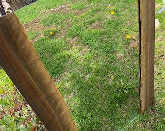 May include: A large rectangular mirror with a rustic wooden frame. The frame is made of natural wood with a dark brown stain. The mirror is reflecting a green grassy lawn with yellow flowers.
