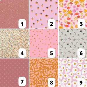 May include: Nine fabric swatches with various patterns. The patterns include small white dots on a dusty rose background, acorns on pink, floral and snail design, floral pattern, orange stars on pink, small flowers, small crescent moons, orange floral design, and fried eggs.