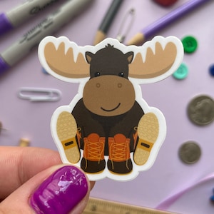 May include: A brown moose wearing brown boots with orange laces and a white background.