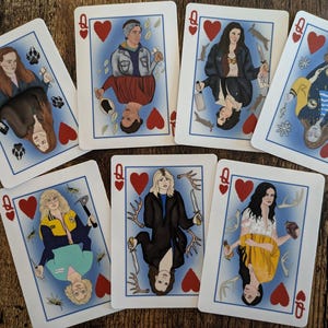 May include: A set of playing cards featuring illustrations of women with different hairstyles and outfits. Each card has a red heart in the corner and the letter Q for Queen.