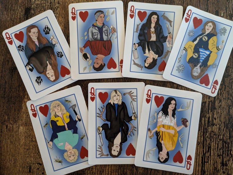 May include: A set of playing cards featuring illustrations of women with different hairstyles and outfits. Each card has a red heart in the corner and the letter Q for Queen.