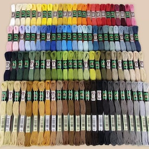 May include: A collection of embroidery floss in a variety of colors, including yellow, blue, green, and brown. The floss is neatly arranged in rows, with each skein labeled. The image showcases a wide range of shades, perfect for crafting projects.