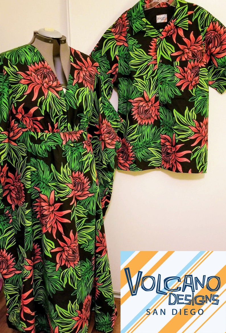 Op de afbeelding: Een bijpassende set zwarte en groene kleding met een bloemenprint met rode bloemen en groene bladeren. De set bevat een lange jurk en een shirt met korte mouwen. De tekst "VOLCANO DESIGNS SAN DIEGO" is zichtbaar in de rechterbenedenhoek van de afbeelding.
