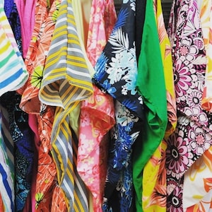 May include: A collection of colorful fabric with floral and striped patterns. The fabrics are hanging in a row and are all different colors and designs.