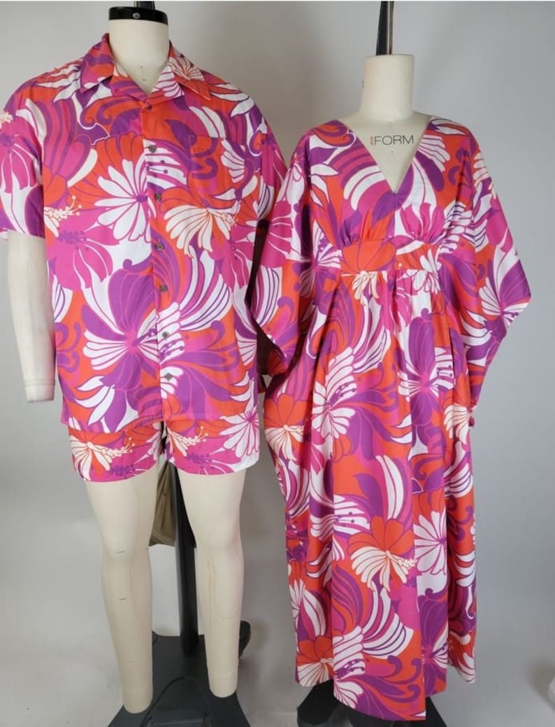 May include: A matching set of pink, orange, and white floral print clothing. The shirt has short sleeves and a button-up front. The pants are shorts. The dress has a V-neck and long sleeves.