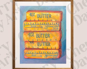 May include: A framed print featuring a stack of four butter sticks. Each stick is labeled "SALTED BUTTER" and "4 OZ" with measurement markings. The artwork has a warm color palette of yellow, orange, and blue.