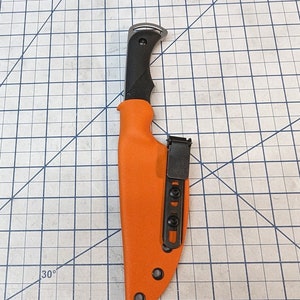 May include: An orange knife sheath with a black belt clip and a black knife handle.