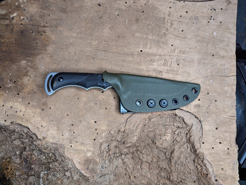 May include: A black and green knife with a textured handle and a sheath with multiple belt loops.