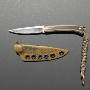 May include: A stainless steel knife with a brown and black handle and a matching sheath. The knife has a pointed blade and a lanyard made of braided cord. The sheath is tan with a topographic pattern.