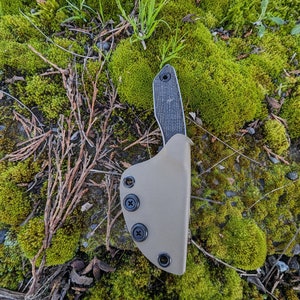 May include: A tan leather knife sheath with three black snaps and a black knife with a textured handle.
