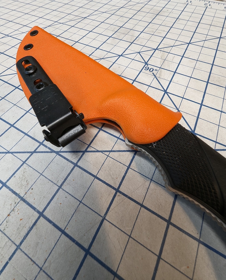 May include: An orange knife sheath with a black clip and a black knife handle with a textured pattern.