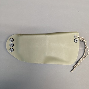 May include: A green leather holster with a brown cord and metal snaps.